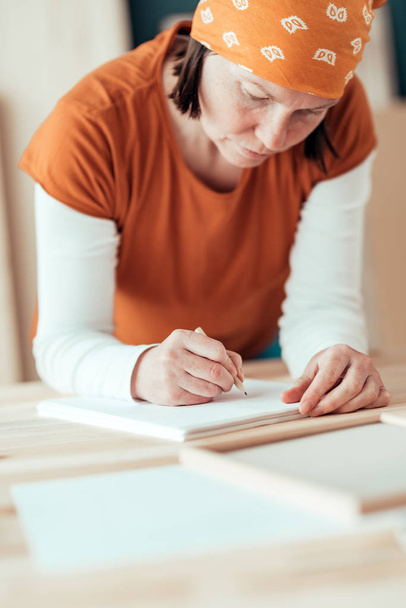 Female carpenter sketching project draft notes in woodwork works - Fotoğraf, Görsel