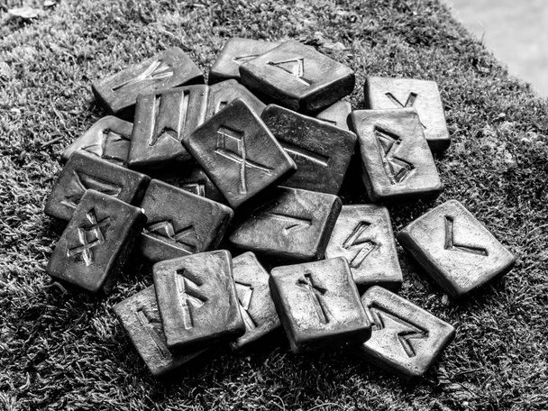 24 norsische Runen auf Gras vor schwarz-weißem Hintergrund. - Foto, Bild