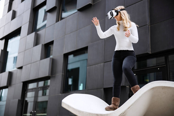 Mulher usando a tecnologia de óculos de realidade virtual contra a construção futurista
 - Foto, Imagem