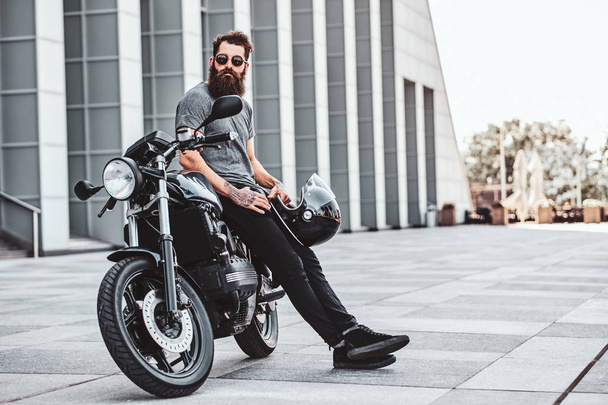 Portret van bebaarde Biker chillen met zijn motor - Foto, afbeelding