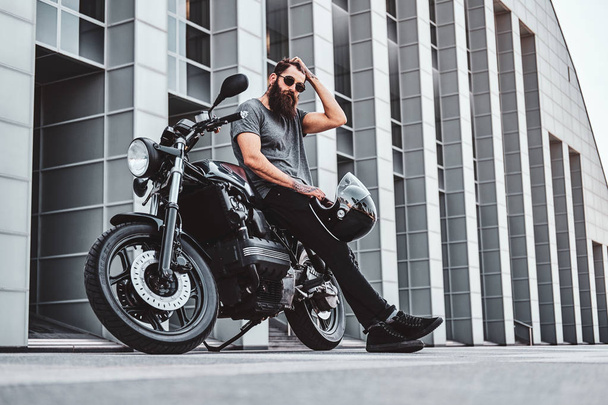 Portrait de motard barbu refroidissant avec sa moto
 - Photo, image