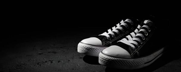 Pair of new black sneakers on dark black background with copy space. - 写真・画像