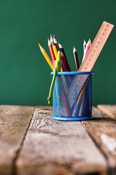 Back to school concept, blue glass with school supplies on a school desk on a background of a clean green chalk board, selective focus, copy space - Photo, Image