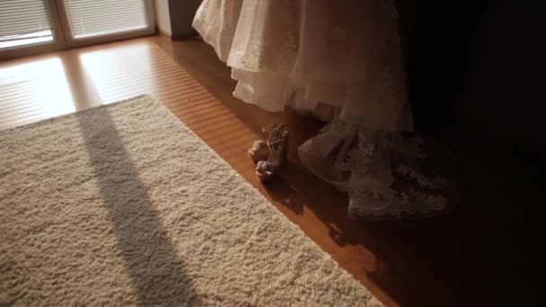 die Schuhe der Bräute auf dem Teppich, die Sonne scheint durch das Fenster des Brautkleides - Filmmaterial, Video