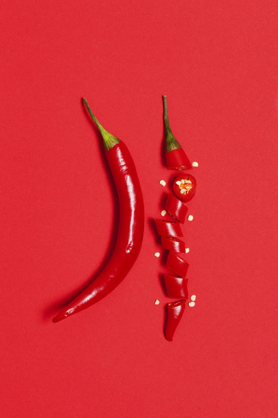 Sliced red chili pepper arranged on a bright red background - Φωτογραφία, εικόνα