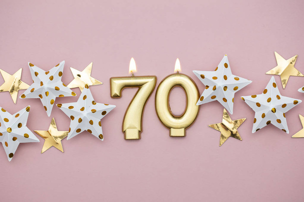 Number 70 gold candle and stars on a pastel pink background - Foto, Imagem