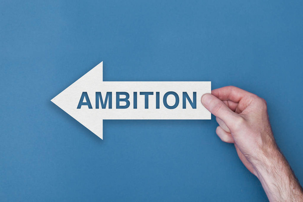 Ambition arrow direction held on a blue background - Fotó, kép