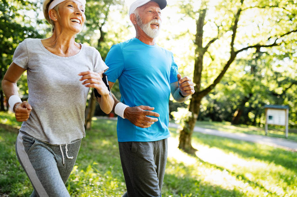 Senior couple jogging and running outdoors in park nature - Zdjęcie, obraz