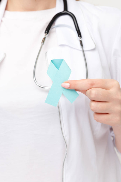 Female doctor holding blue ribbon isolated. - Foto, Imagem