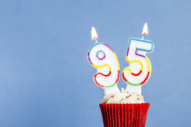 Número 95 vela de cumpleaños en un cupcake sobre un fondo azul
 - Foto, Imagen
