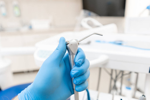 Close-up hand of dentist in the glove holds Gun dental water and air. . Office where dentist conducts inspection and concludes. Office where dentist conducts inspection and concludes. - 写真・画像