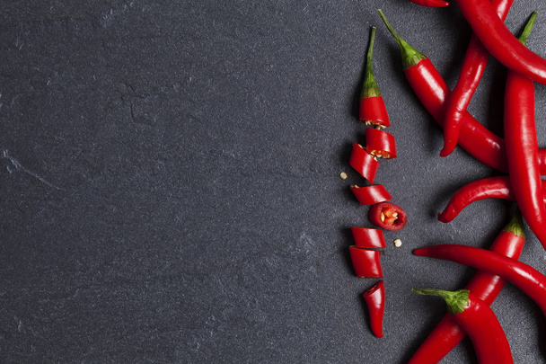 Red fresh chili pepper chopped into pieces on a dark slate backg - Photo, Image