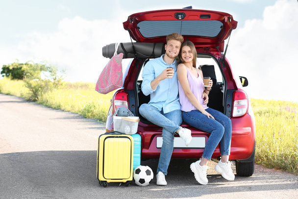 Young couple with luggage near car trunk outdoors - Valokuva, kuva
