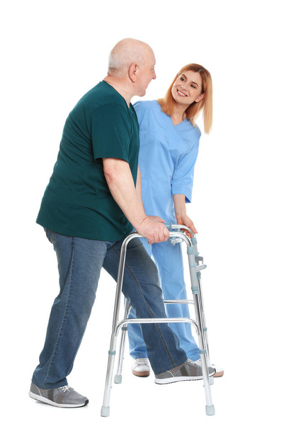 Caretaker helping elderly man with walking frame on white background - Photo, image