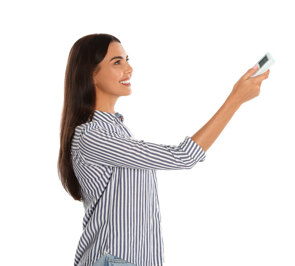 Jovem mulher ligando ar condicionado contra fundo branco
 - Foto, Imagem
