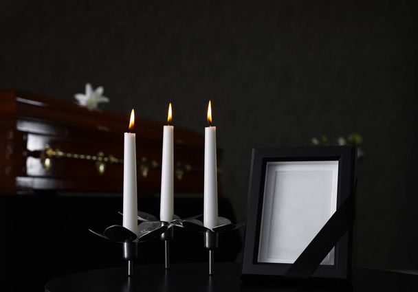 Black photo frame with burning candles on table in funeral home - Zdjęcie, obraz