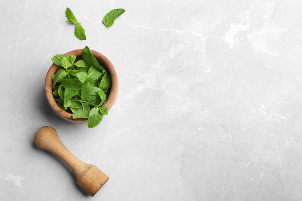 Fresh mint with mortar and pestle on grey marble background, flat lay. Space for text - Photo, Image