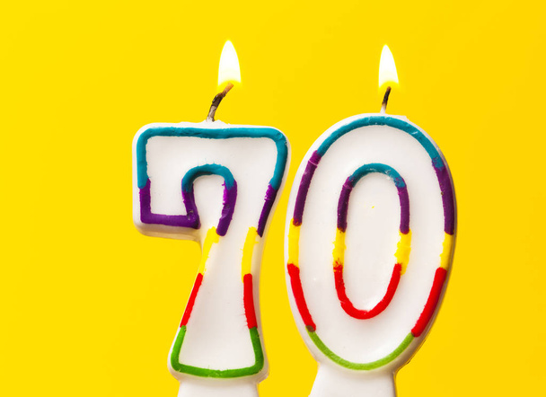 Number 70 birthday celebration candle against a bright yellow ba - Zdjęcie, obraz