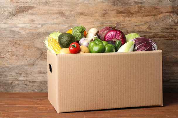 Fresh vegetables in cardboard box on wooden table - Foto, immagini