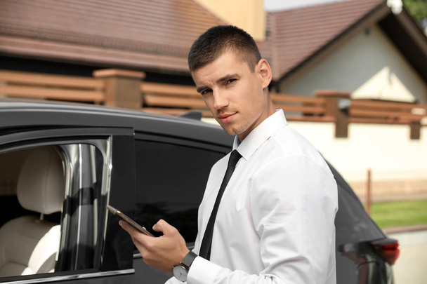 Attractive young man with smartphone near luxury car outdoors - Φωτογραφία, εικόνα