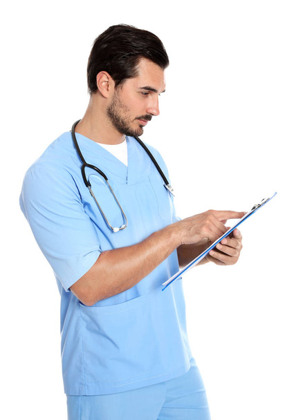 Young male doctor in uniform with stethoscope and clipboard on white background. Medical service - Foto, afbeelding