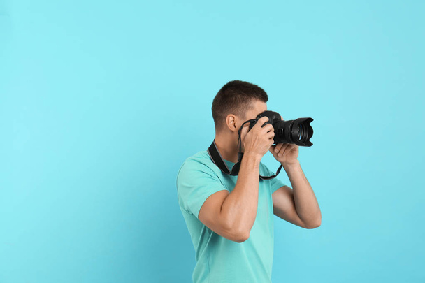 Young professional photographer taking picture on light blue background. Space for text - Photo, image