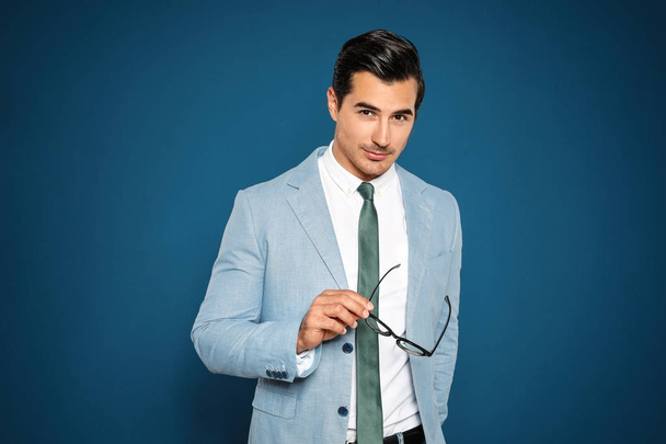 Portrait of handsome young man in suit on blue background - Photo, image