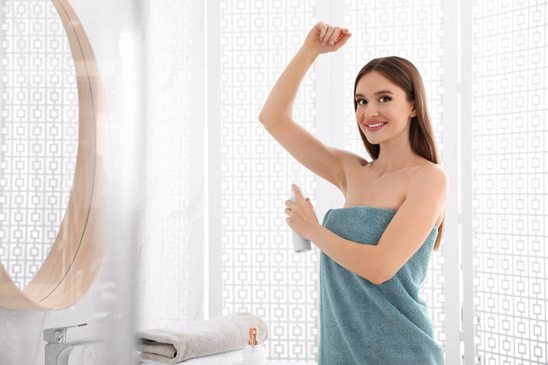 Beautiful young woman applying deodorant after shower in bathroom - Foto, afbeelding