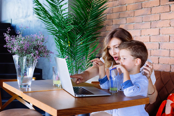 Mom and her son looking at laptop at the table. She is showing him something. - 写真・画像