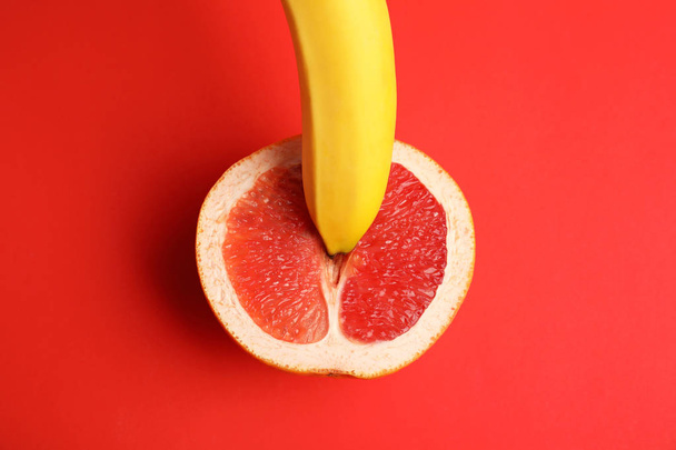 Fresh grapefruit and banana on red background, top view. Sex concept - Foto, Imagen