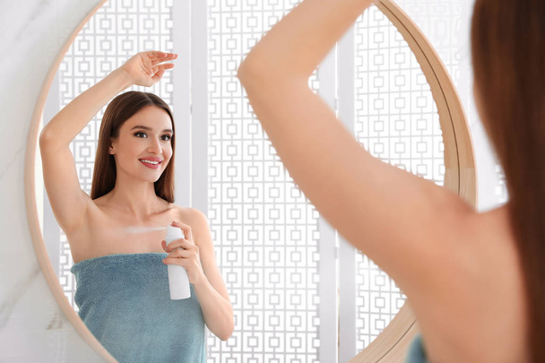 Beautiful young woman applying deodorant after shower in bathroom - Photo, image