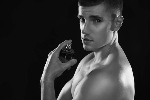 Handsome young man using perfume, black and white effect - 写真・画像