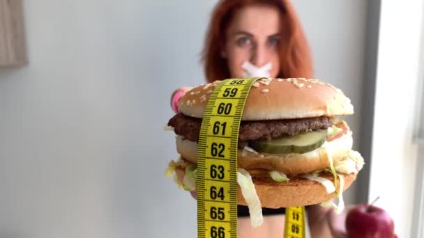 Dieta. Retrato de uma mulher quer comer um hambúrguer, mas uma boca colada, uma noção de dieta, comida insalubre, uma vontade em nutrição
 - Filmagem, Vídeo