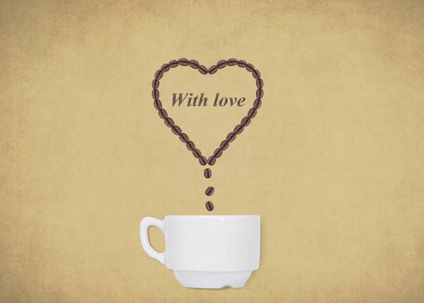 Coffee dripping to a cup from a heart which is made of coffee beans. A symbol of love and care in a minimalist style - Photo, Image