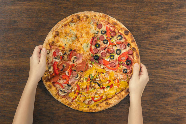 Arka planda arka planda desteklenen pizza ve ellerin yakın çekim - Fotoğraf, Görsel