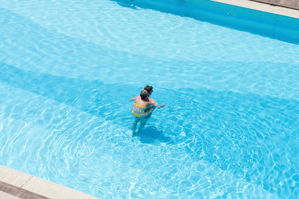 Aerial view on boy  in the swimming pool with transparent blue water. In the motion  - Foto, immagini