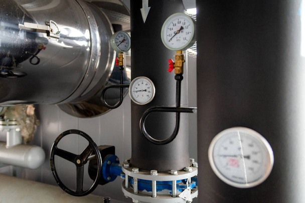 The equipment of the boiler-house, - valves, tubes, pressure gauges, thermometer. Close up of manometer, pipe, flow meter, water pumps and valves of heating system in a boiler room - Photo, Image