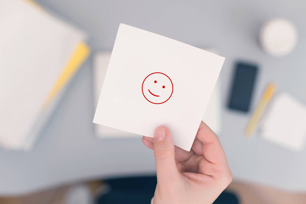 Woman clerk in the office holding paper sticker with positive smile icon.  - 写真・画像