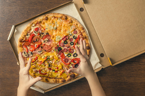 Female hands open delivery box with pizza. - Zdjęcie, obraz