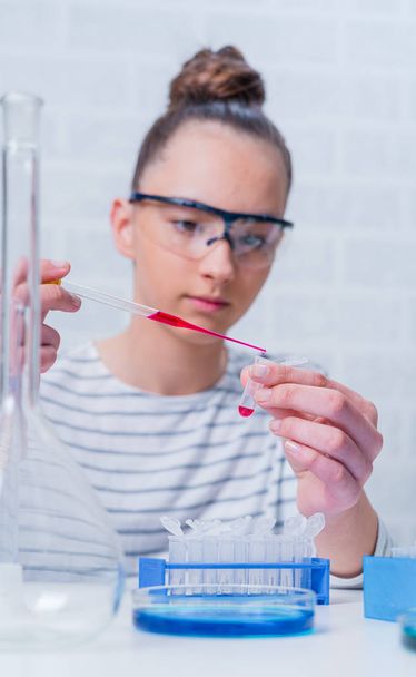 Teen girl student caring out experiments in chemistry class. - Foto, Bild