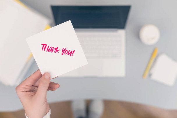 Woman clerk in the office holding paper sticker with the word: Thank you!  concept  - Fotó, kép