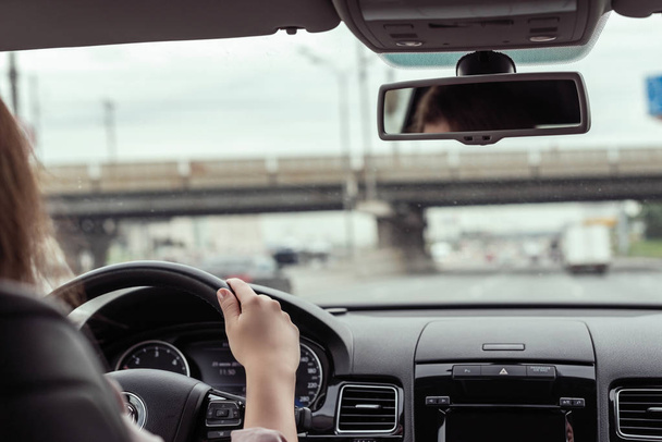 γυναίκα οδηγεί στην εθνική οδό κάτω από τη γέφυρα. Θέα από το πίσω κάθισμα του αυτοκινήτου  - Φωτογραφία, εικόνα