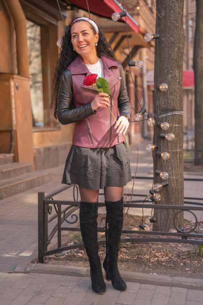 junges hübsches Mädchen mit langen Haaren und roter Rose in der Stadt - Foto, Bild