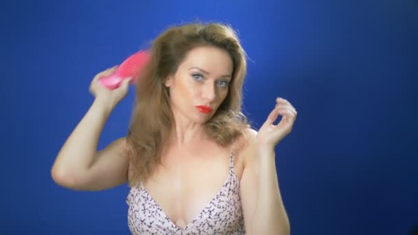 concepto de chica pin-up. Mujer pin-up endereza su cabello, mirando a la cámara, fondo azul. espacio de copia
 - Metraje, vídeo