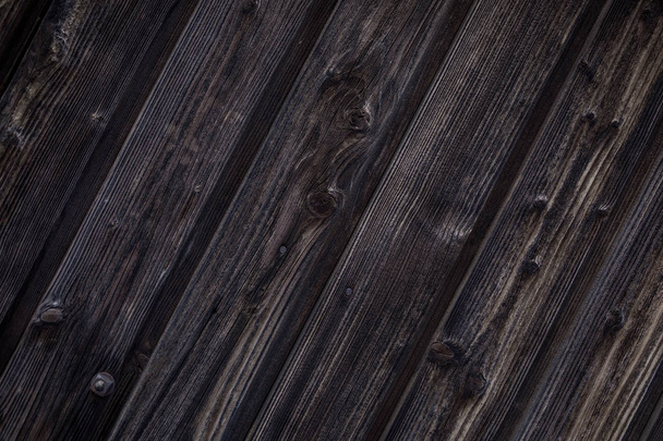 Темно-коричневый деревянный фон. Натуральные деревянные доски насыщены темным маслом. Вертикальные доски с узлами, гвоздями и болтом расположены под углом
. - Фото, изображение