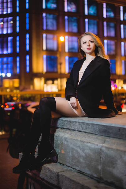 portrait of Beautiful young woman in black on a background of a night city - Foto, imagen
