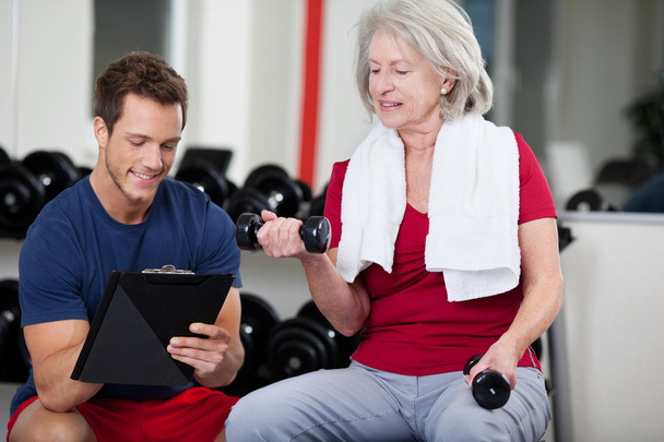 Trainer instructing a senior woman in the gym - Foto, immagini