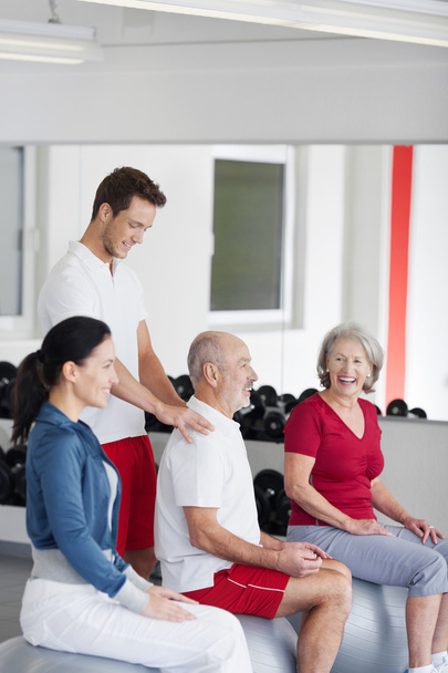 Trainer helping a senior man at the gym - Foto, Imagen