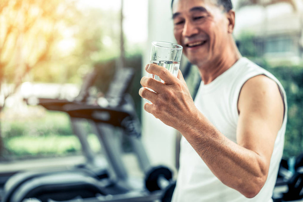 Senior man drink mineraalwater in het fitnesscentrum. - Foto, afbeelding