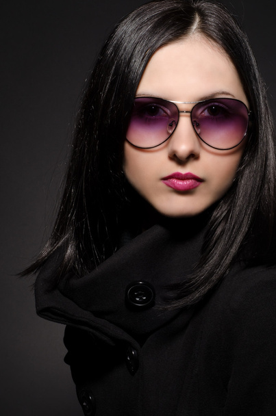 Portrait of a beautiful girl in sunglasses on black background - Foto, afbeelding